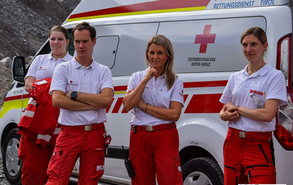 drei Sanitäterinnen und ein Sanitäter stehen nach einem Einsatz vor ihrem Rettungsauto